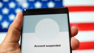 Close up of hand holding smartphone showing "Account Suspended" from a social media application.