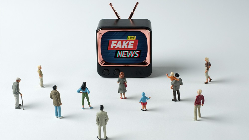 Figurines watching "fake news" on TV.