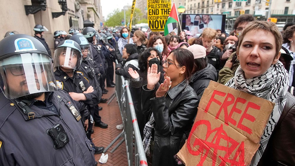 Police stand in riot gear as demonstrators chant outside the Columbia University campus.