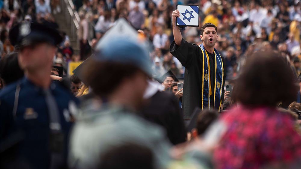 A graduate holds his cap with an Israeli flag during the University of Michigan's Commencement Ceremony on May 4, 2024.