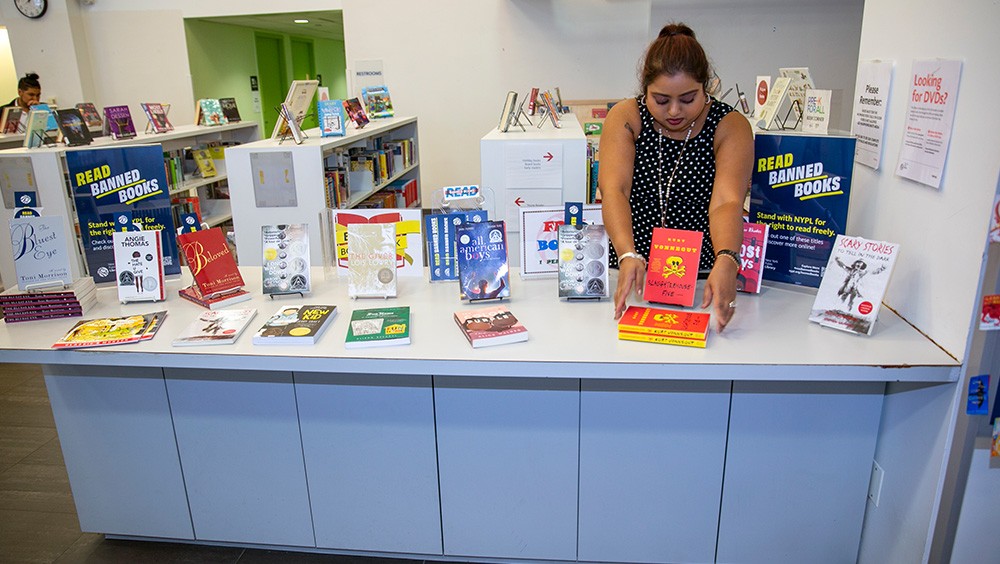A librarian arranges a display of banned books during Banned Books Week at a New York Public Library branch in 2022.
