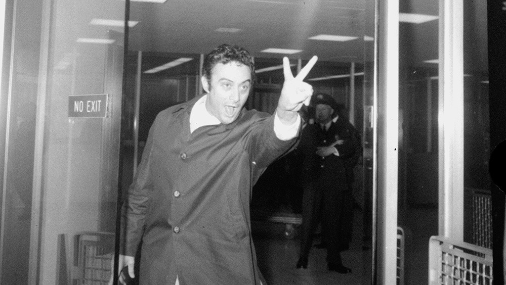 Comedian Lenny Bruce, refused entry to Britain, makes a V-sign as he leaves the U.S. customs office after returning to New York in 1963.