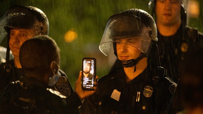 A man recording police as they stand watch during a 2020 protest in Rochester, New York.