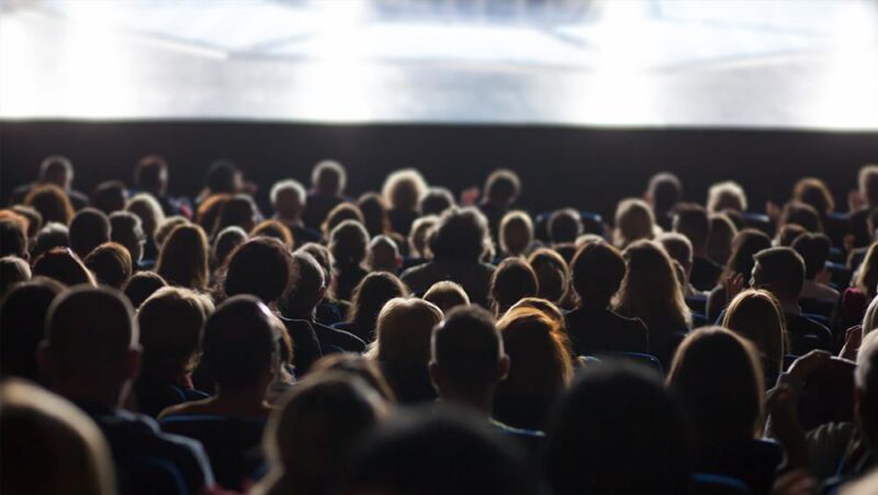 Rear view of people in crowded theater watching movie