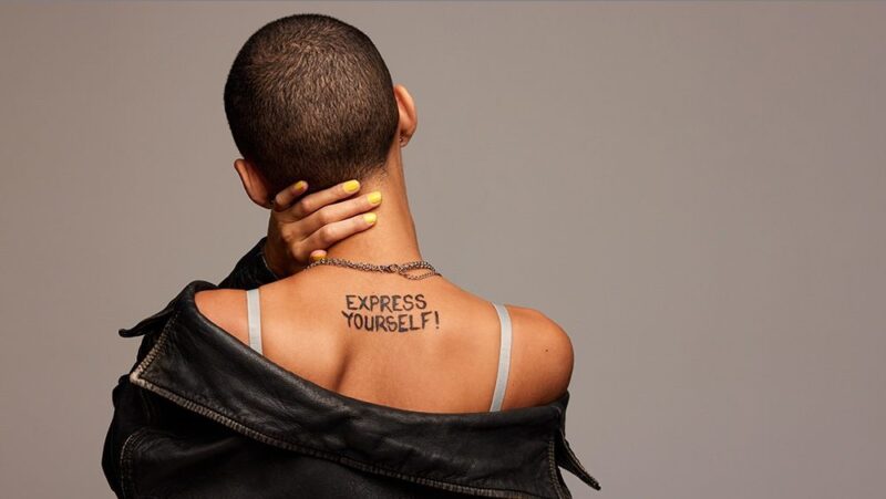 Rear view of anonymous woman with express yourself written on back.