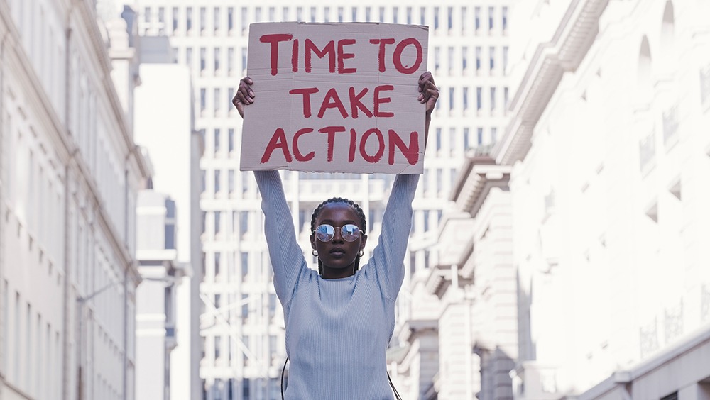 Woman protestor holding sign reading "time to take action"